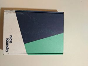 A rectangular shipping box with Nice Laundry in the bottom-right corner. There are three colors on the box: blue, light green, and white.